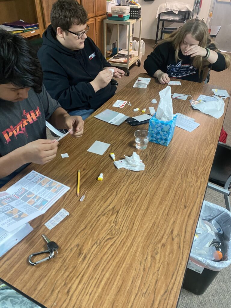 3 students work on the project sitting at a table