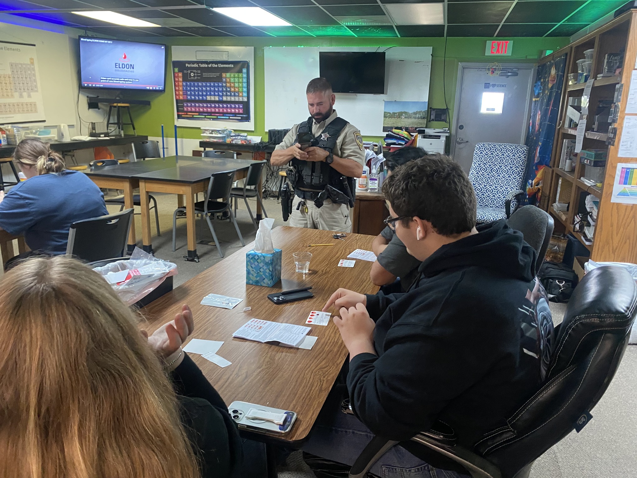 4 Students sitting at a table watching a presentation by the campus patrol officer