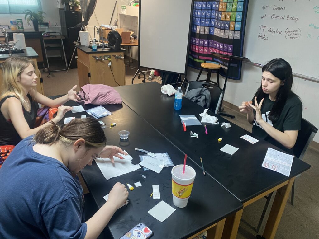 3 Students doing science experiments sitting at a table